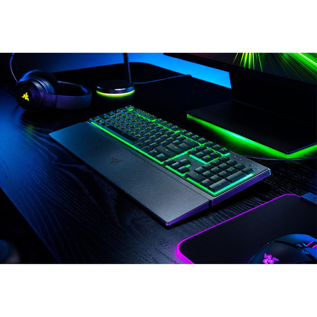 Razer gaming keyboard with green backlighting on a dark desk setup