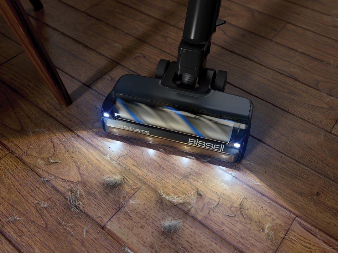 BISSELL handStickVacuum head with lights illuminating pet hair on a wooden floor