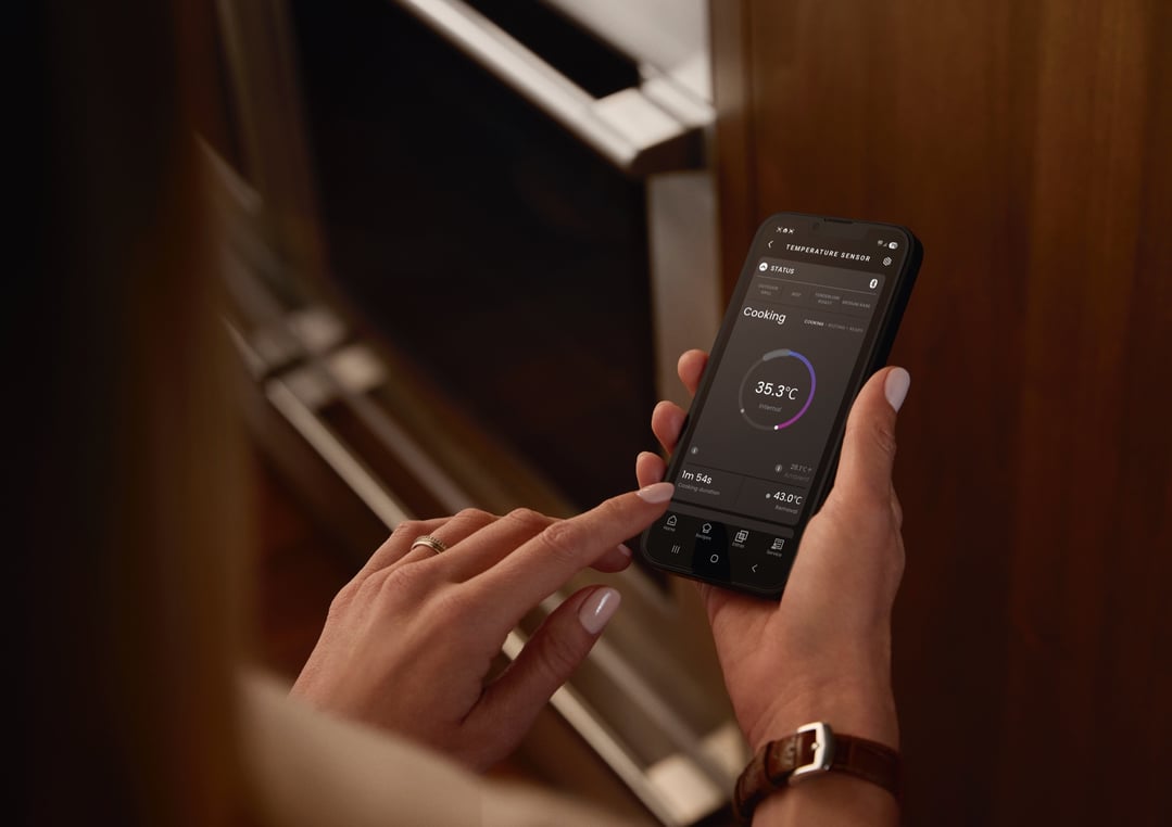 Person holding a smartphone displaying a temperature sensor app