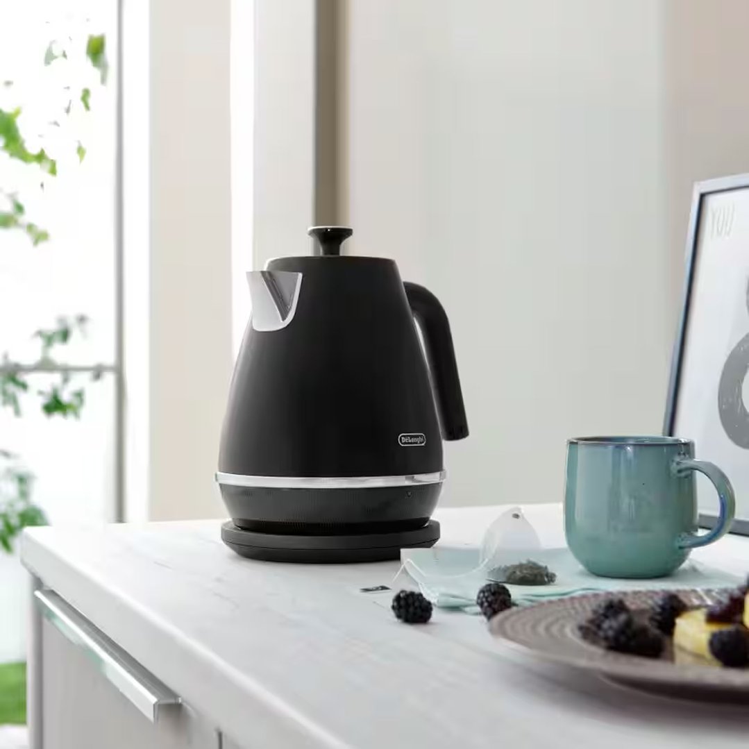 Black kettle on a white countertop with a mug and berries
