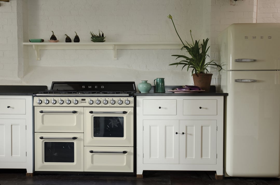 Cream freestanding dual fuel oven/stove and refrigerator in a white kitchen