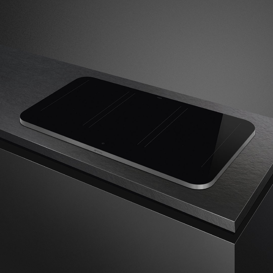 Black induction cooktop with silver trim on a dark countertop