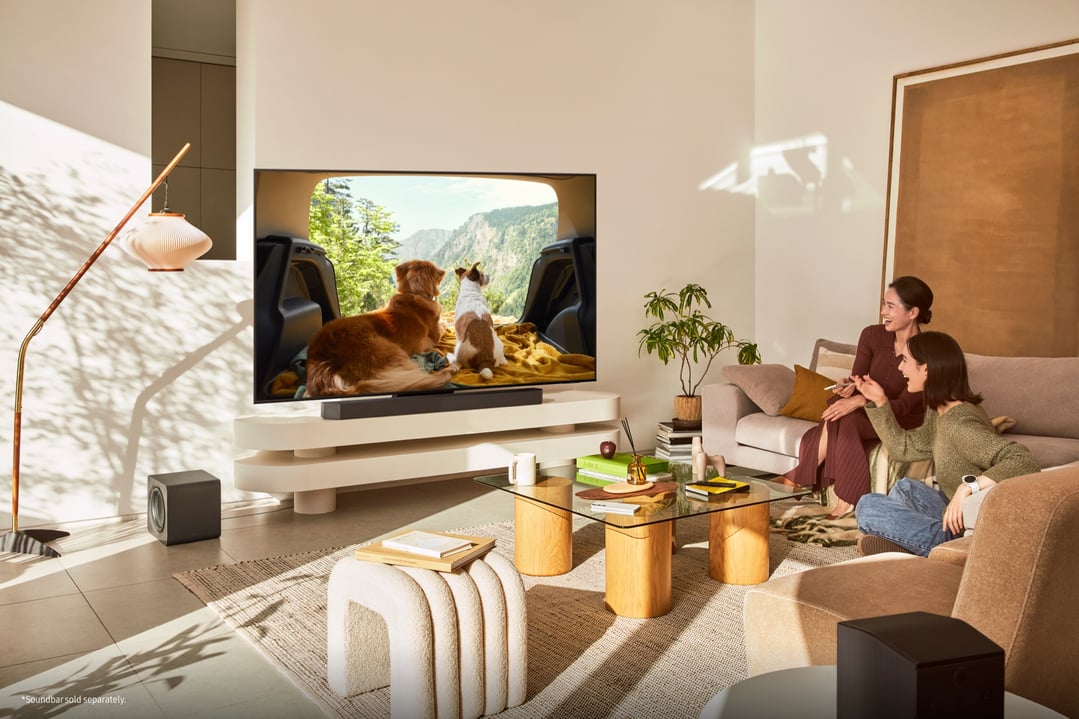 Two women watching a TV on a stand in a living room