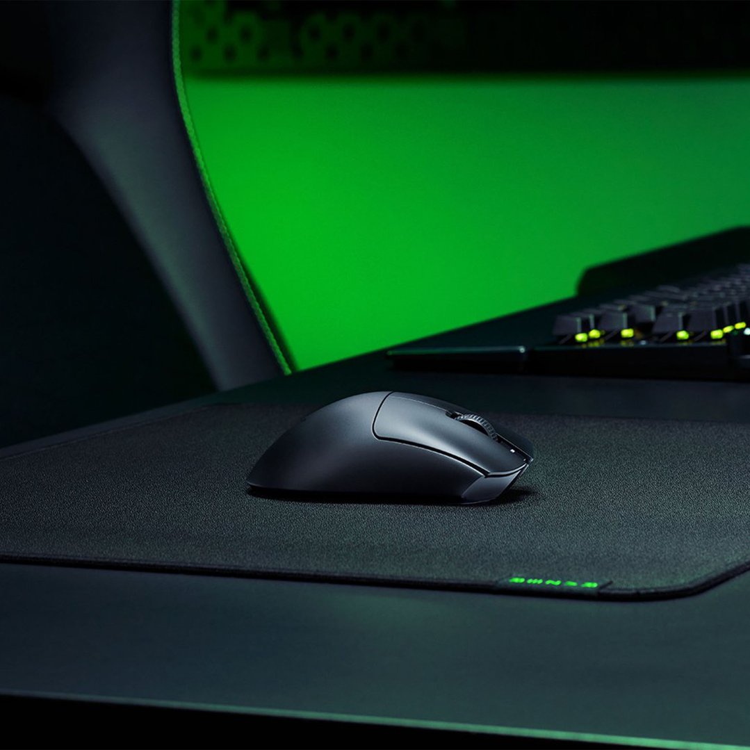 Black gaming mouse on a mouse pad with a green background