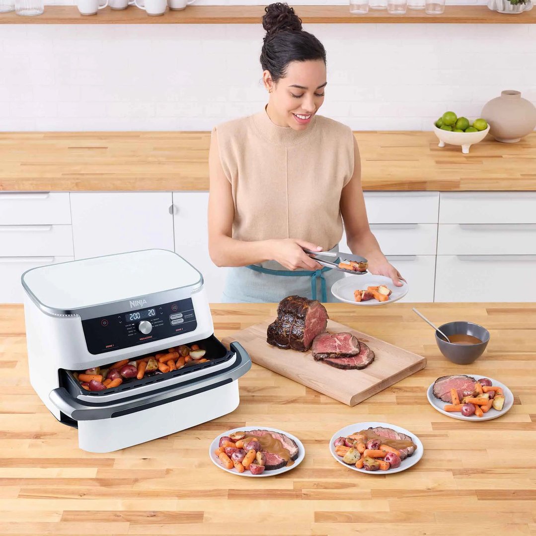 Woman serving roasted meat and vegetables from a Ninja air fryer