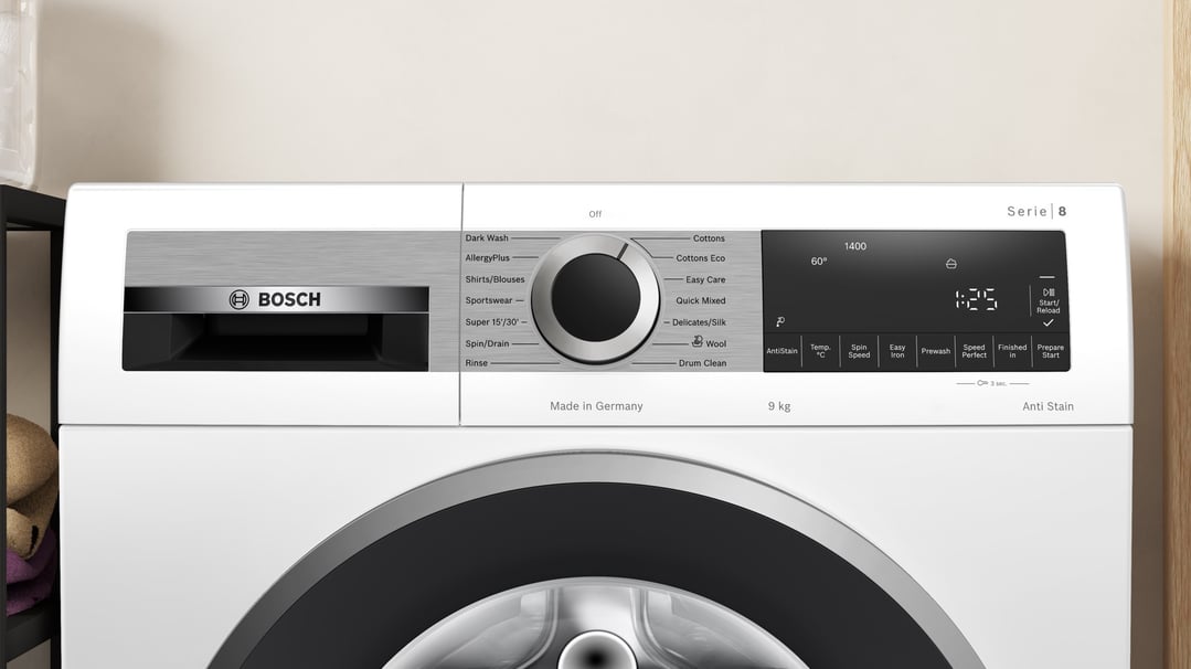 Close up of a white Bosch washing machine control panel and door