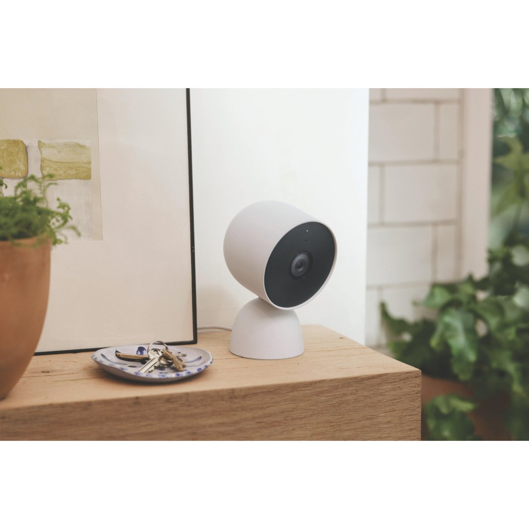 Nest Cam security camera on a wooden surface with keys and a plant