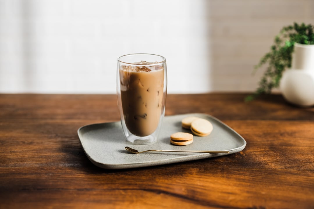 Iced coffee in a glass on a tray with cookies and a spoon