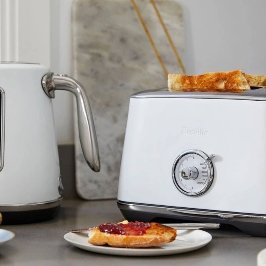 White Breville toaster and kettle on a kitchen counter with toast and jam