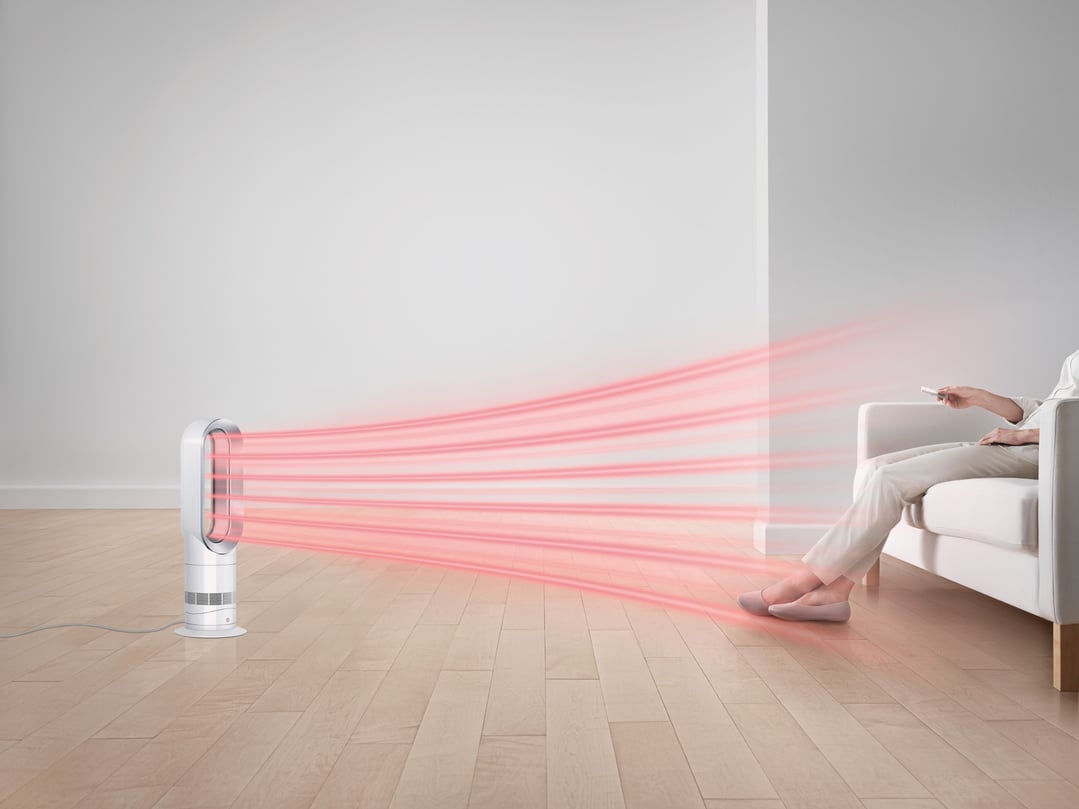 Dyson Hot+Cool fan heater projecting red heat beams towards a person on a sofa