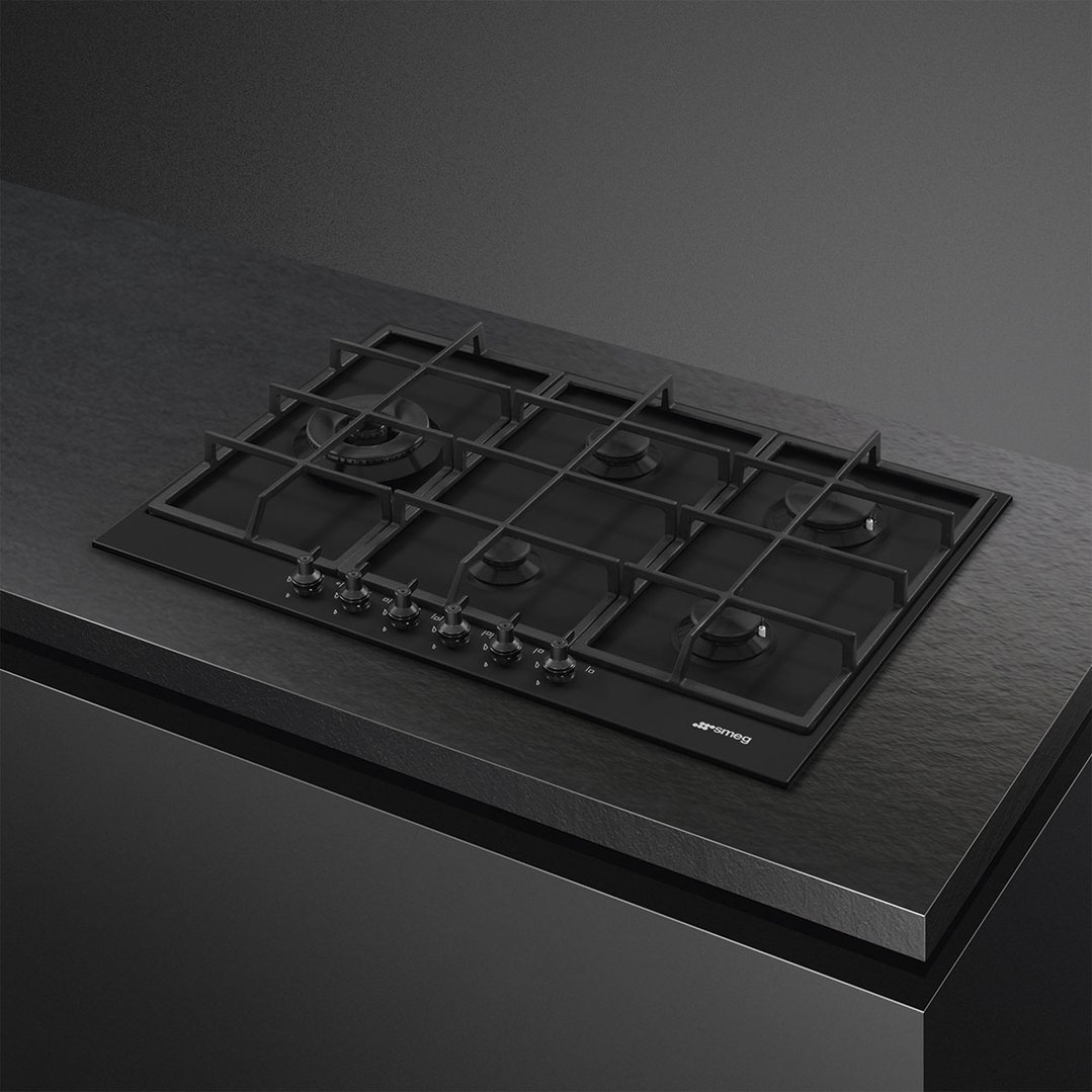 Matte black gas cooktop with six burners and controls built into a dark countertop