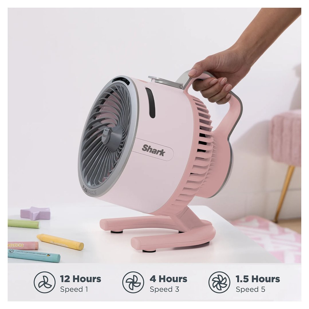 Hand holding a pink Shark FlexBreeze portable fan on a white table with crayons