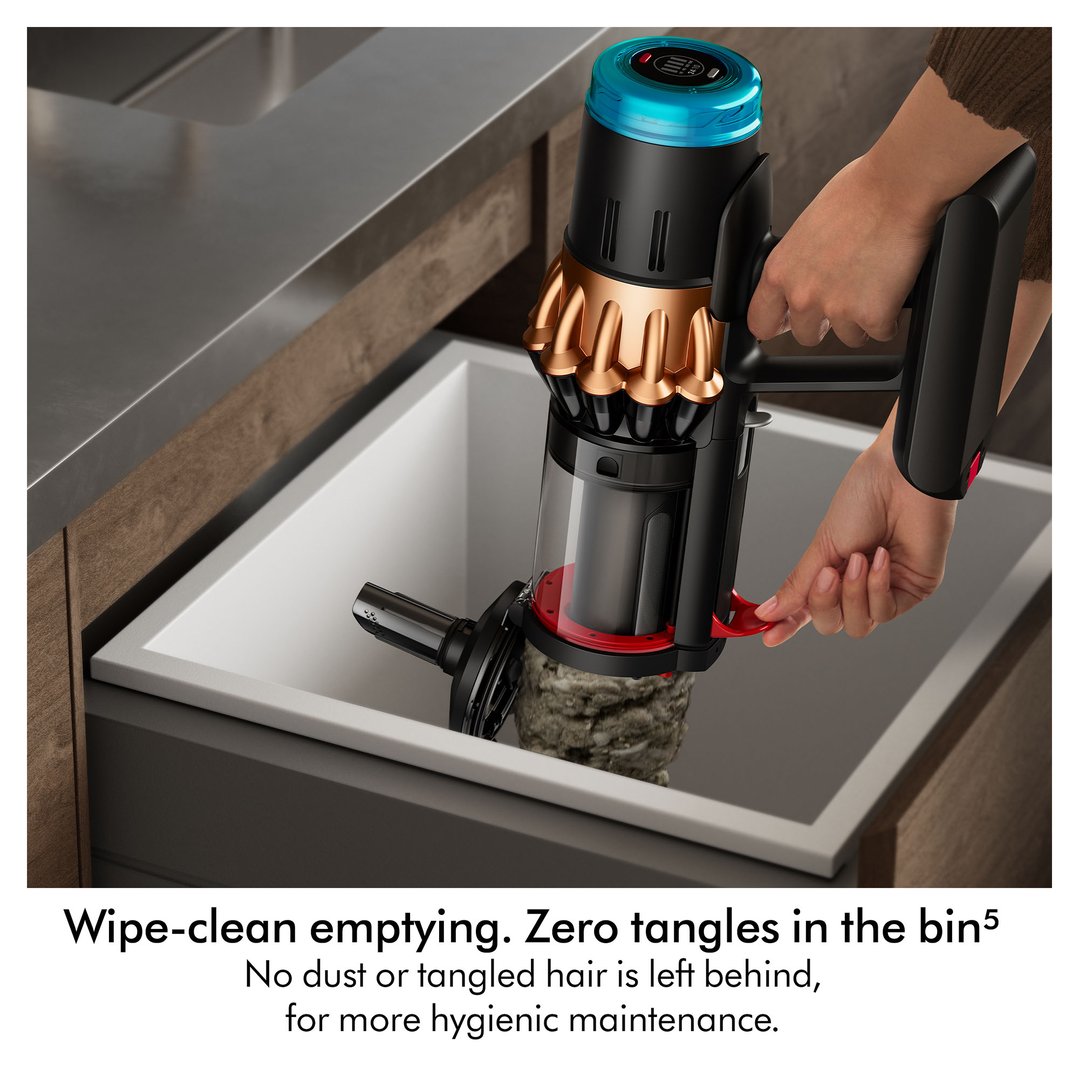 Hand emptying a Dyson handstick vacuum cleaner into a white bin