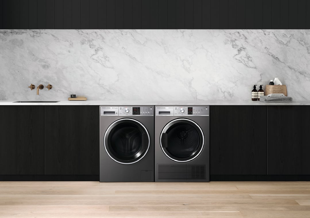 Two washing machines in a modern laundry room with marble backsplash