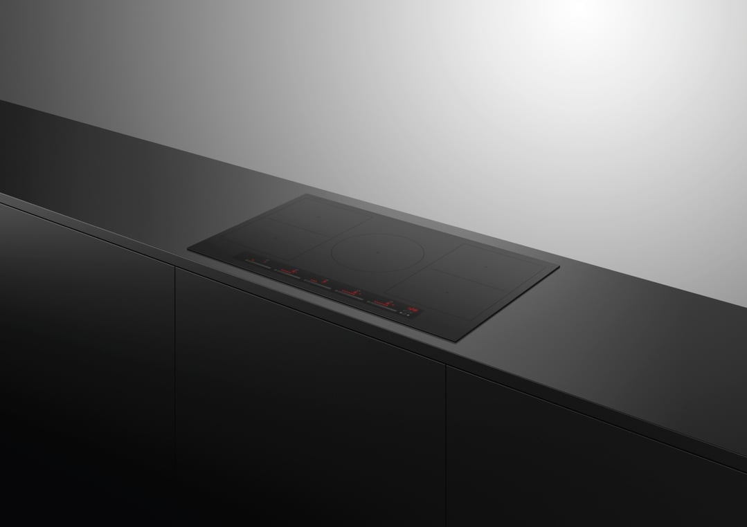 Black induction cooktop with red illuminated controls built into a dark kitchen counter