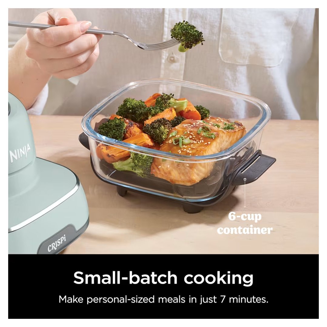 Hand holding a fork with broccoli over a Ninja air fryer container