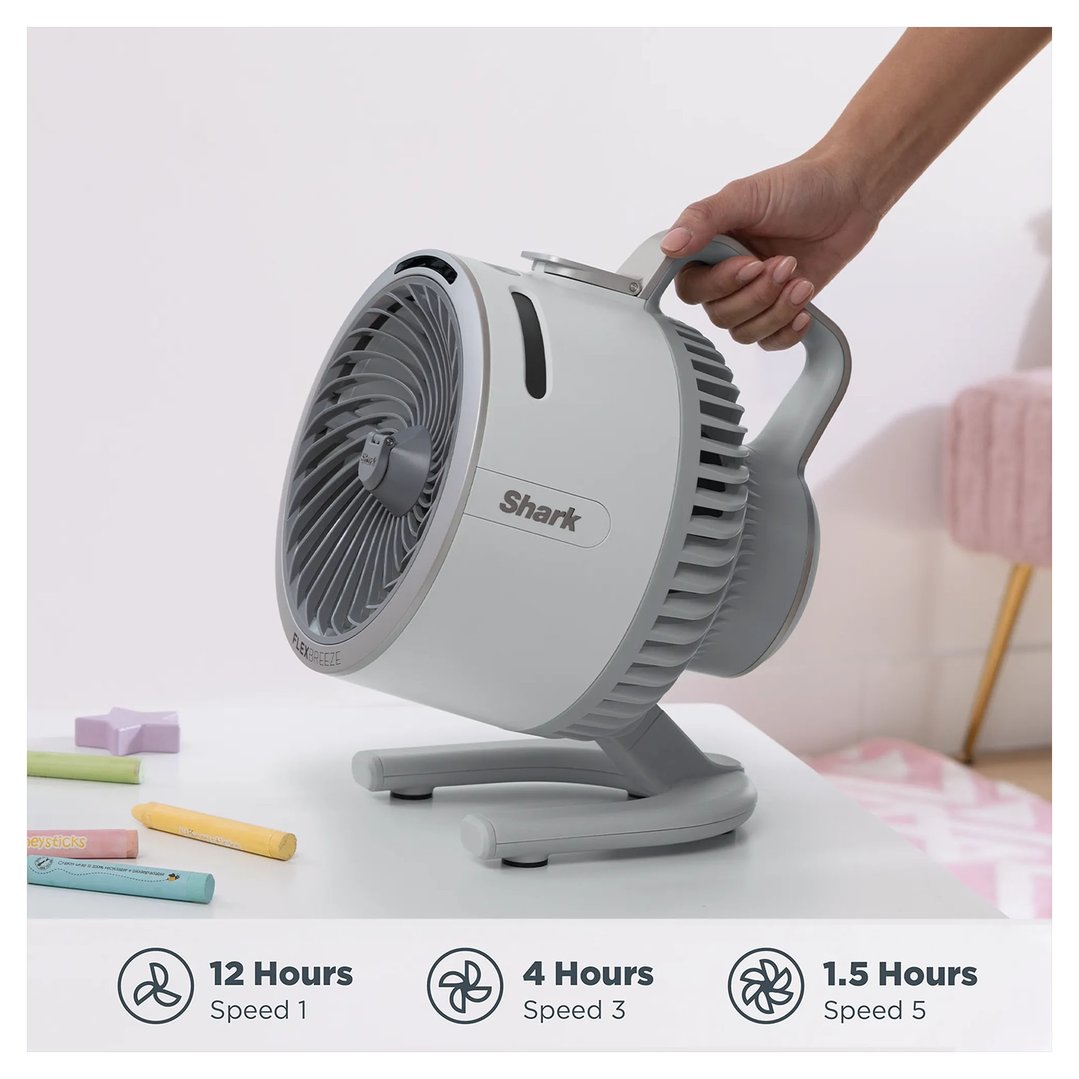 Hand holding a Shark FlexBreeze portable fan on a white table with crayons