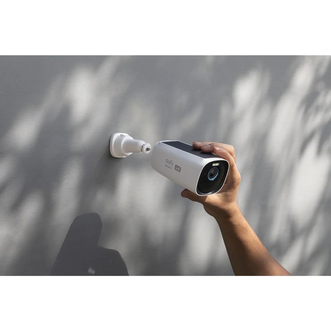 Hand installing a white security camera onto a wall mount