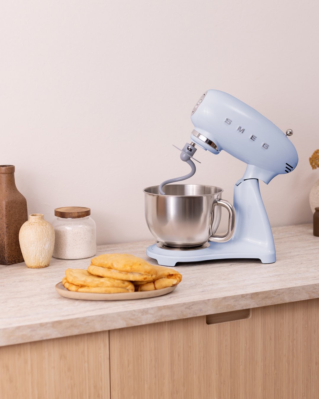 Pastel blue Smeg stand mixer on a kitchen counter with pastries and jars