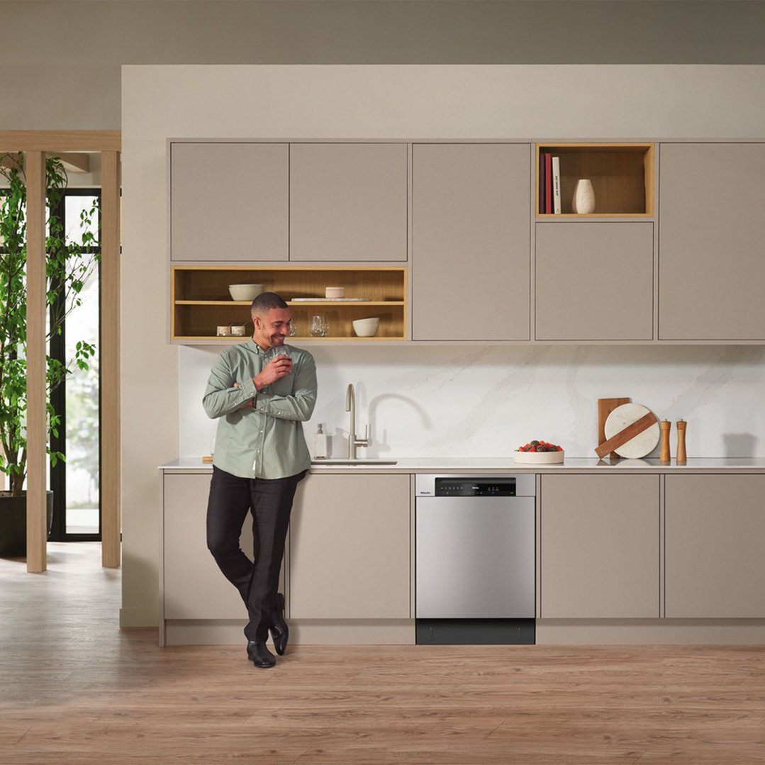 Man leaning on kitchen counter with a built-under dishwasher in a modern kitchen