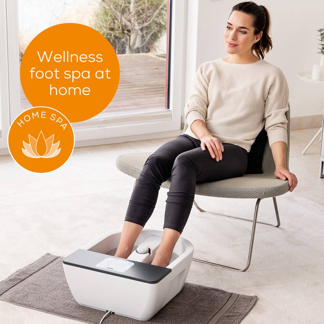 Woman sitting on a chair using a foot spa in a living room