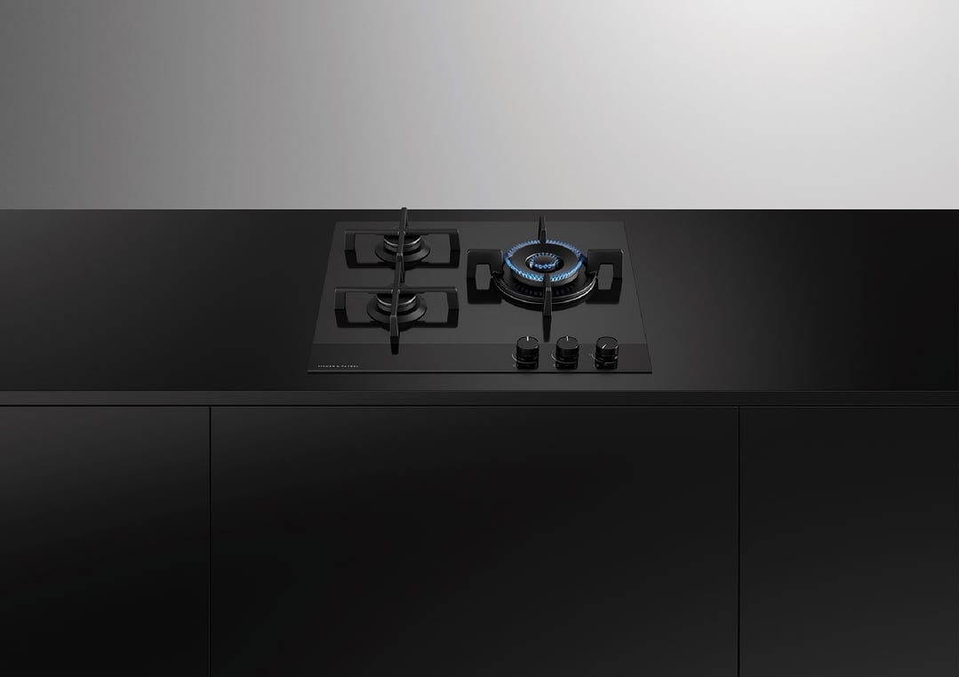 Black gas on glass cooktop with one burner lit in a modern kitchen