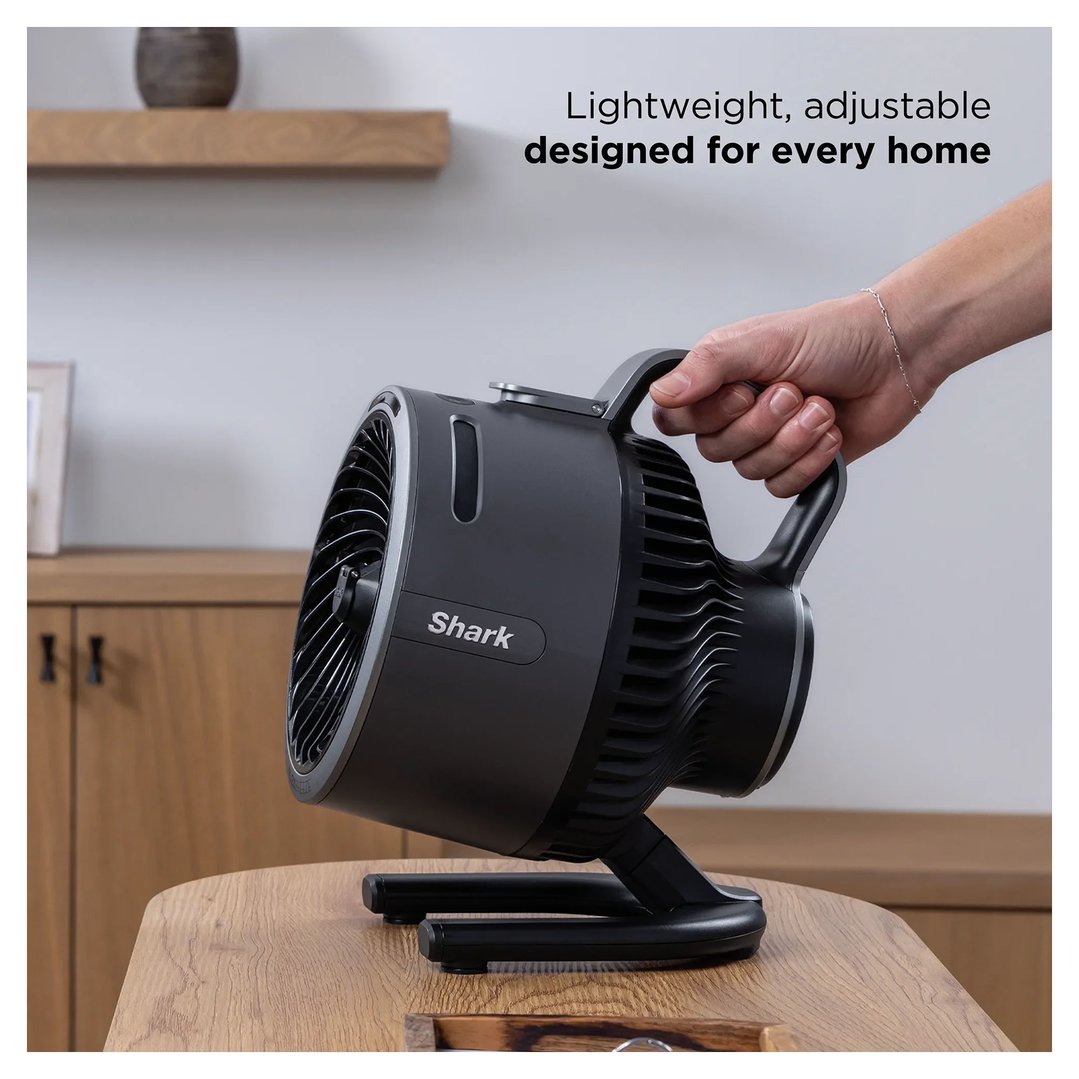 Hand holding a Shark portable fan on a wooden table