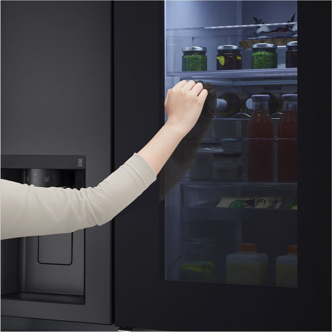 Hand reaching into the open door of a matte black side by side fridge