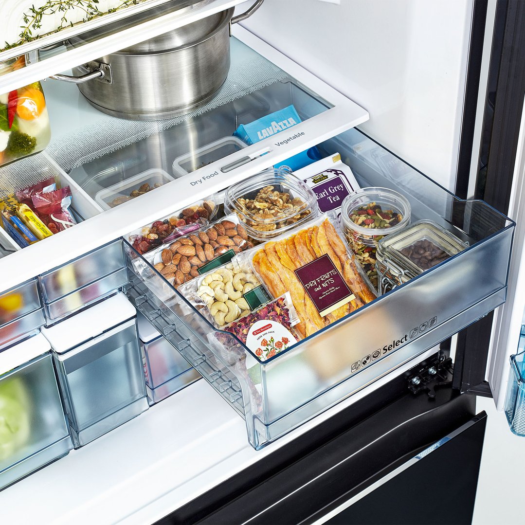 Open fridge drawer filled with various dry foods, nuts, and tea bags
