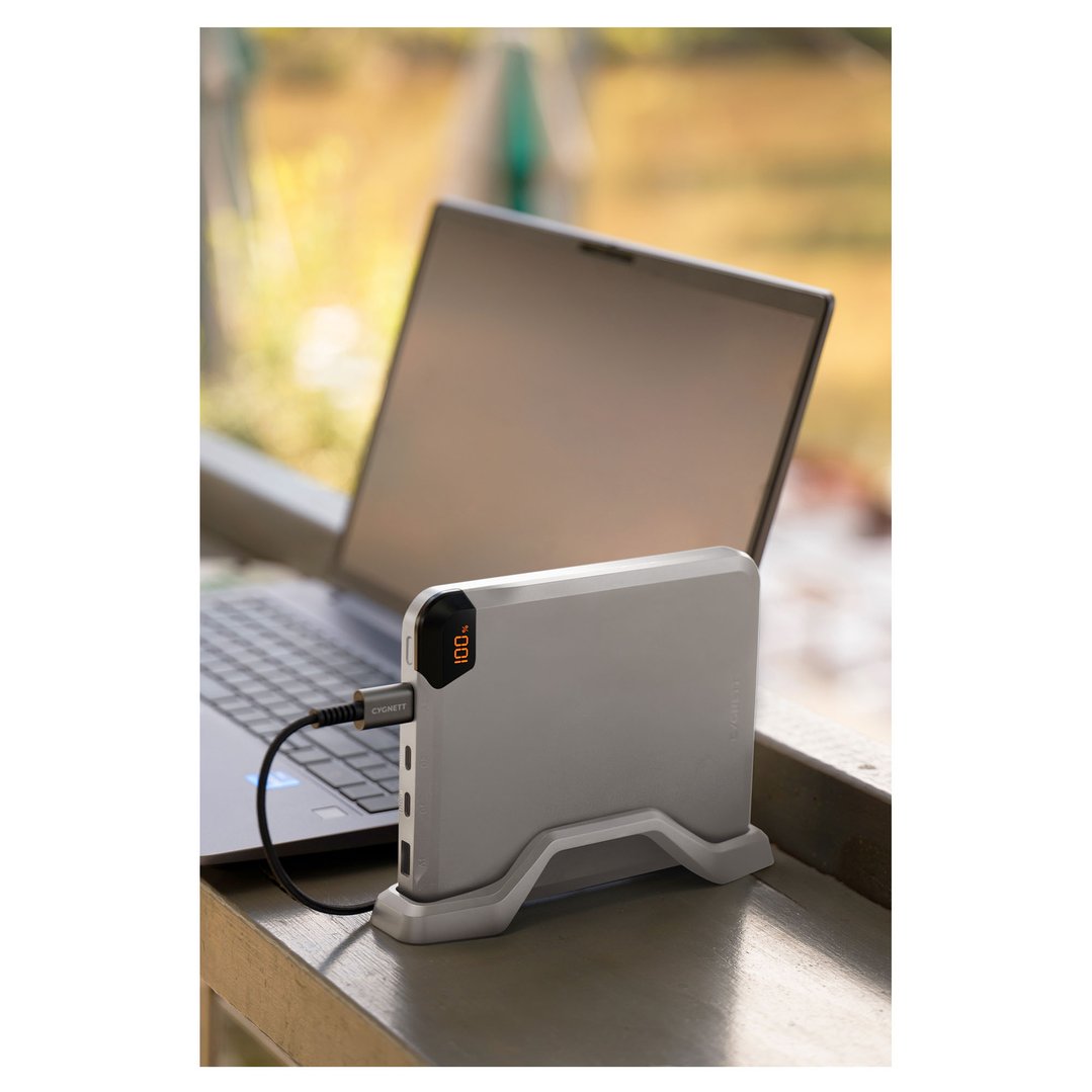 A power bank charging a laptop, displayed on a wooden surface outdoors