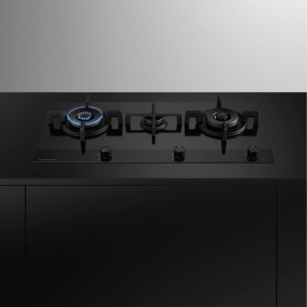 Black gas on glass cooktop with one burner lit in a modern kitchen