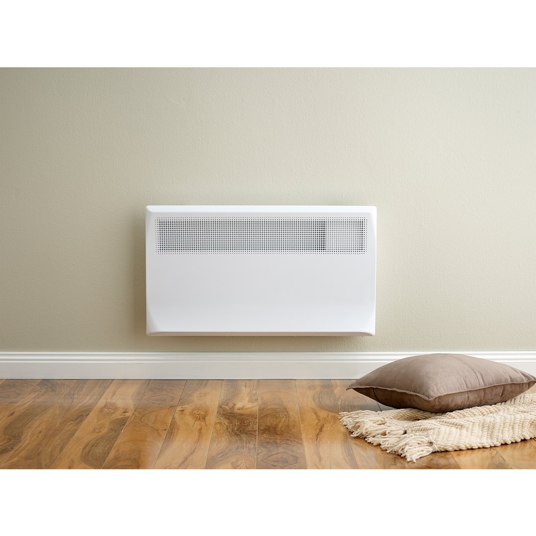 White electric panel heater mounted on a beige wall above a wooden floor