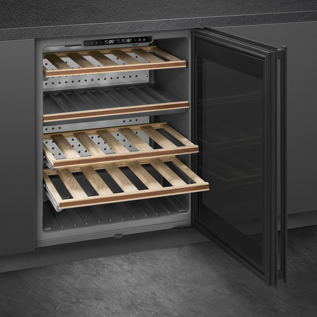 Built-in wine cooler with wooden shelves and open door in a dark kitchen setting