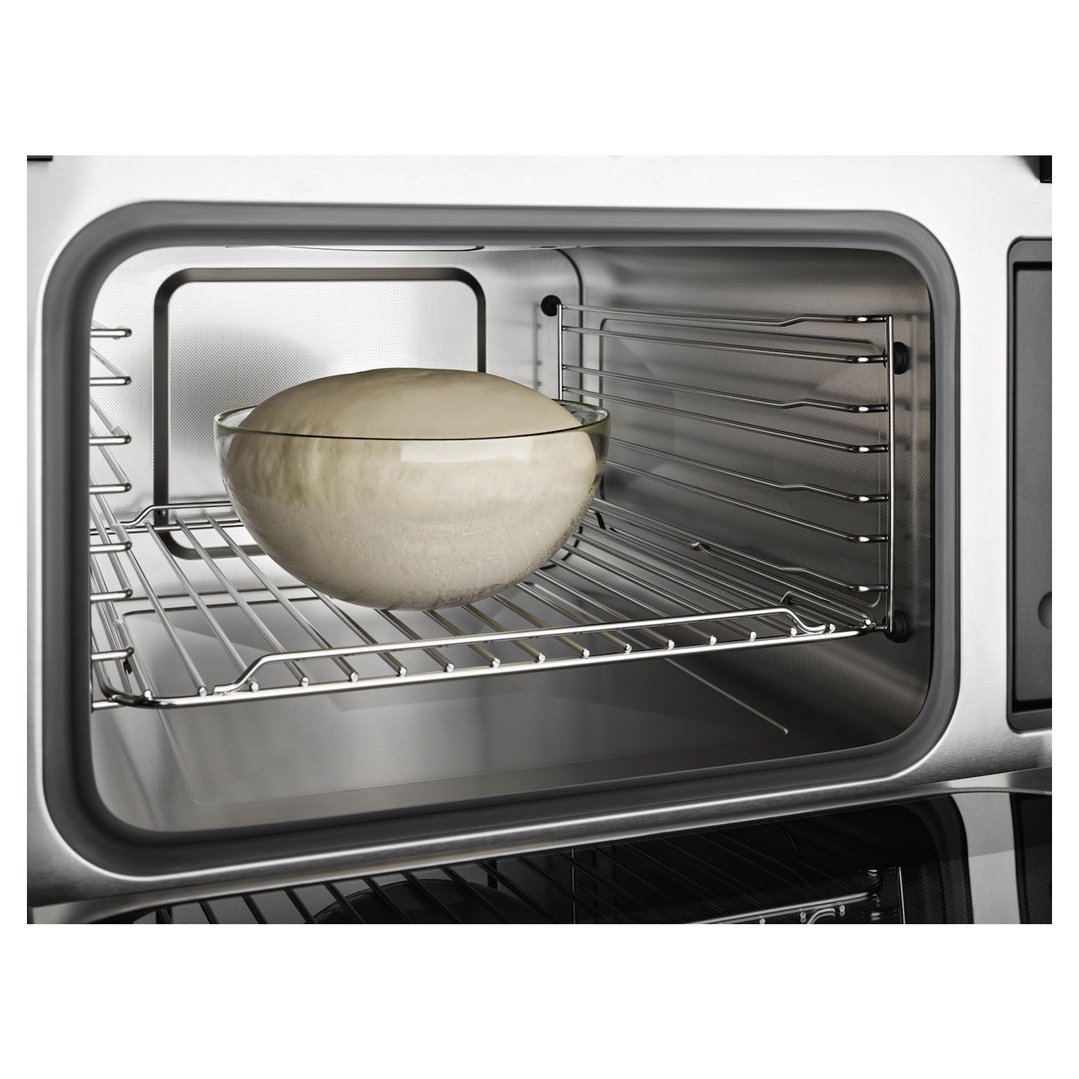 Dough in a glass bowl inside a microwave combination oven on a wire rack