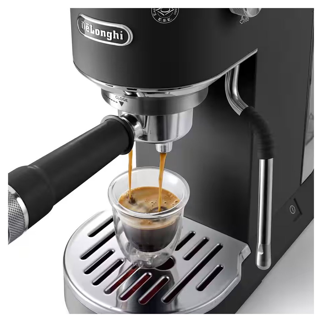 Black DeLonghi coffee machine dispensing espresso into a glass cup