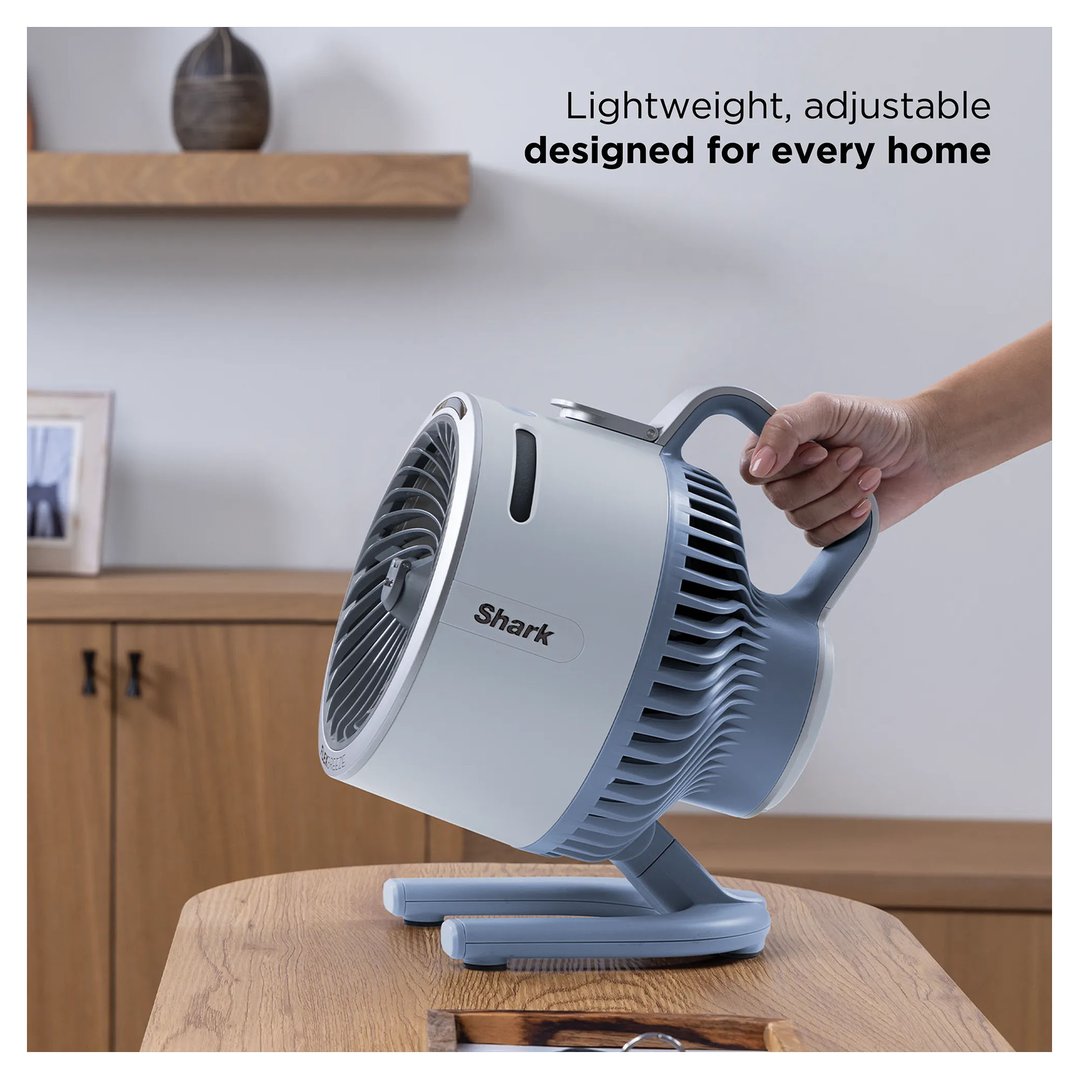 Hand holding a Shark FlexBreeze portable fan on a wooden table