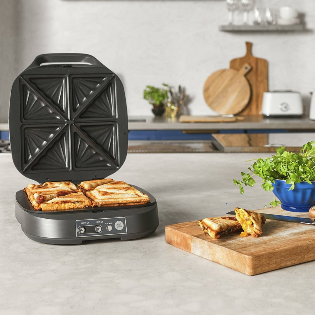 The Power Toastie sandwich maker open with two cooked sandwiches inside on a kitchen counter