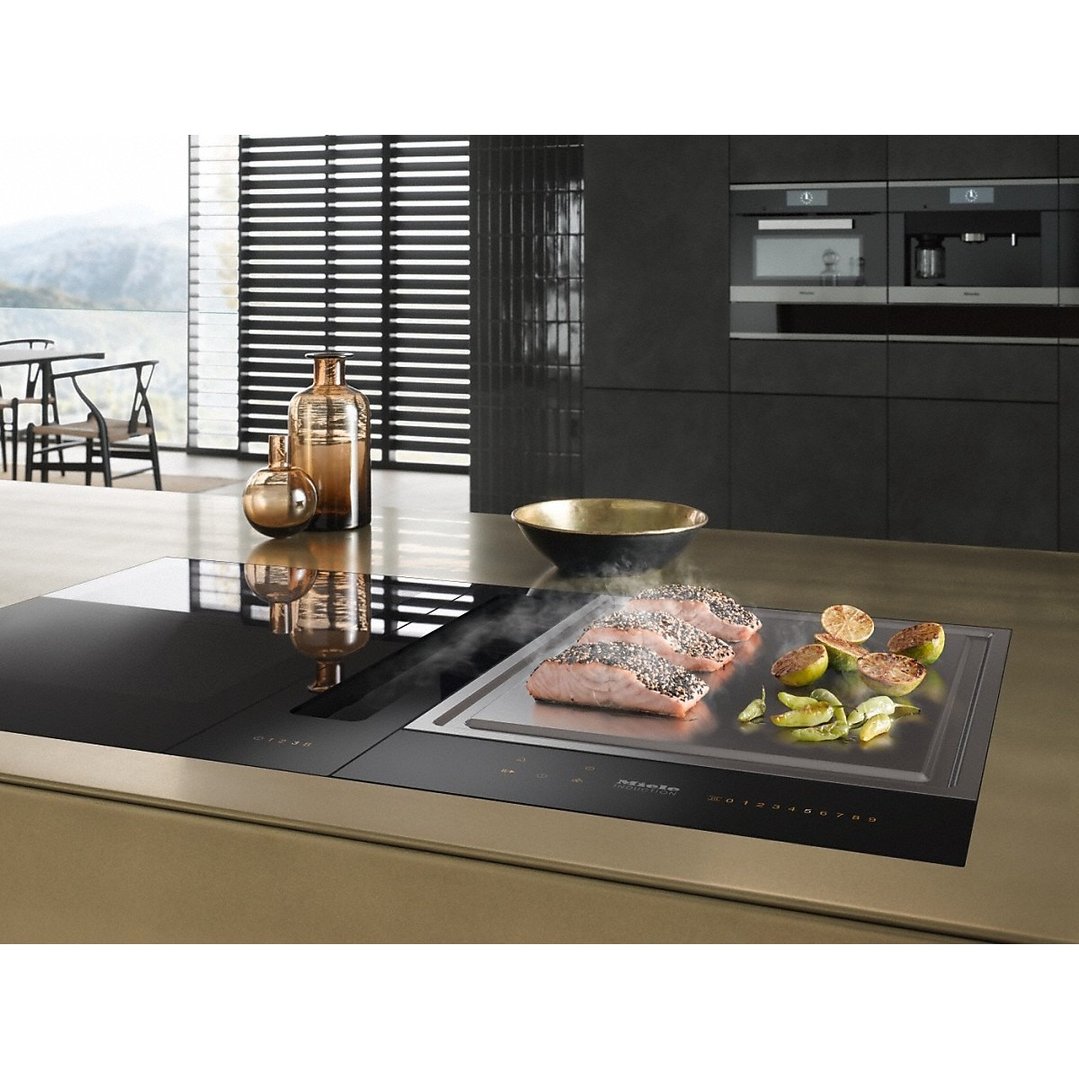 Salmon and vegetables cooking on a Teppanyaki cooktop in a modern kitchen