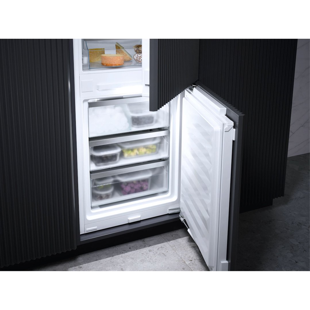 Open integrated fridge freezer showing interior shelves with food items