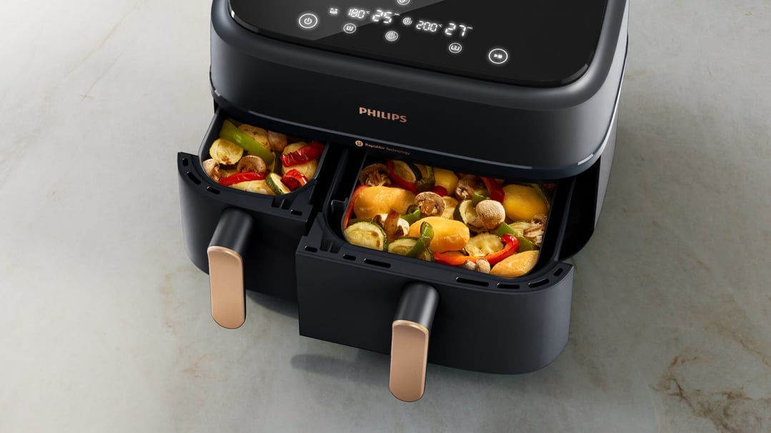 Dual basket airfryer with vegetables in baskets on a marble countertop