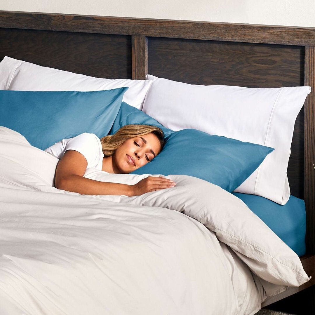 Woman sleeping soundly in a bed with white and blue bedding