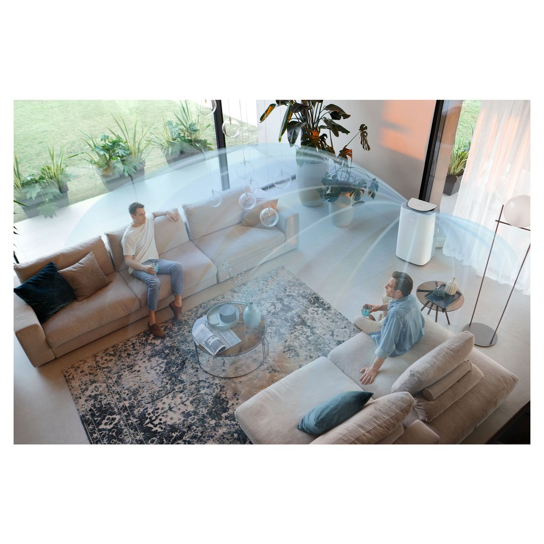 Two men relaxing on sofas in a living room with a portable air conditioner