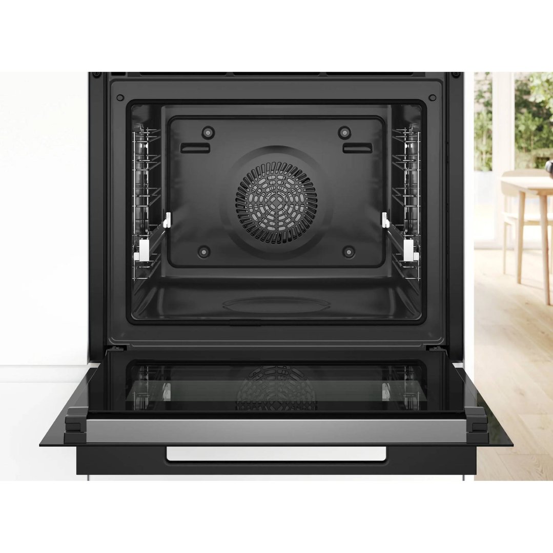 Open black built-in oven with a fan and racks inside a kitchen