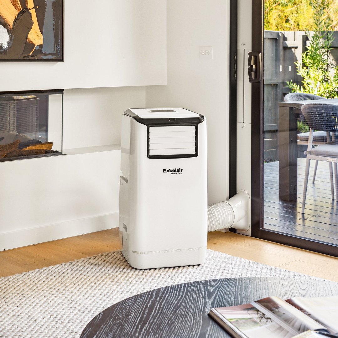White portable air conditioner in a living room with a fireplace and outdoor view