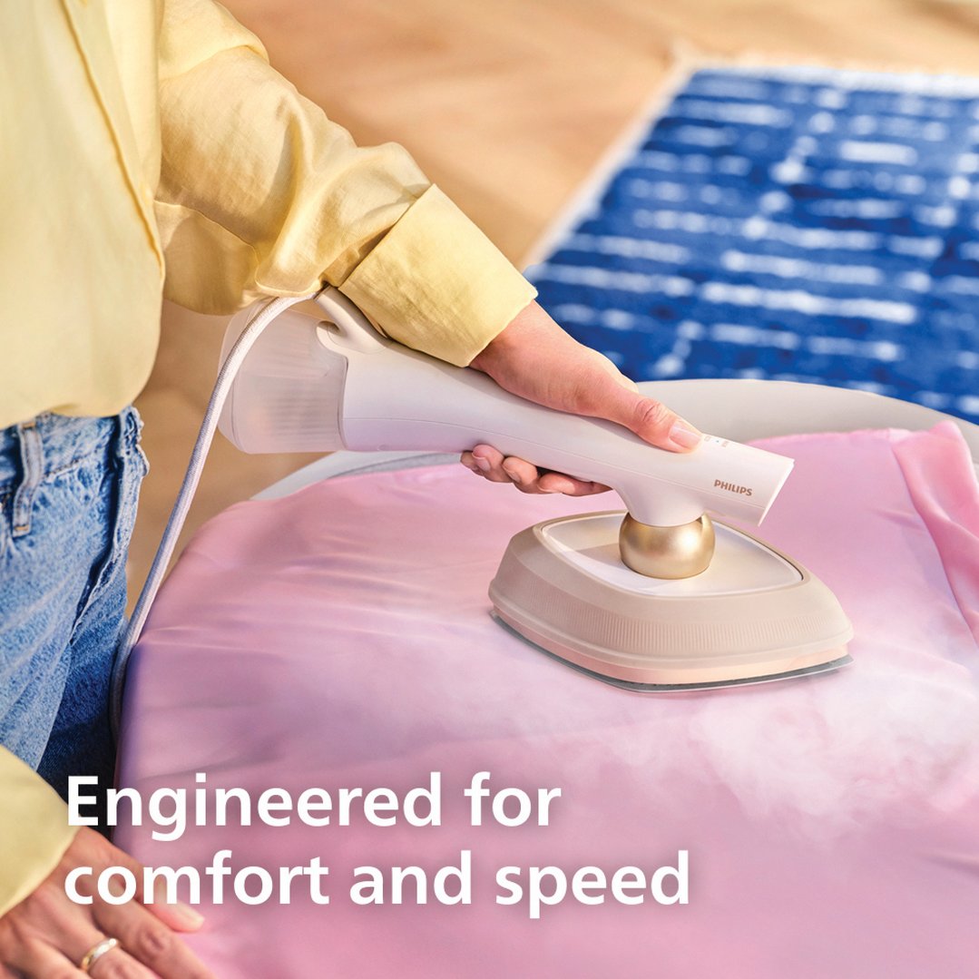 Woman's hands using a Philips hybrid iron and steamer on a pink garment