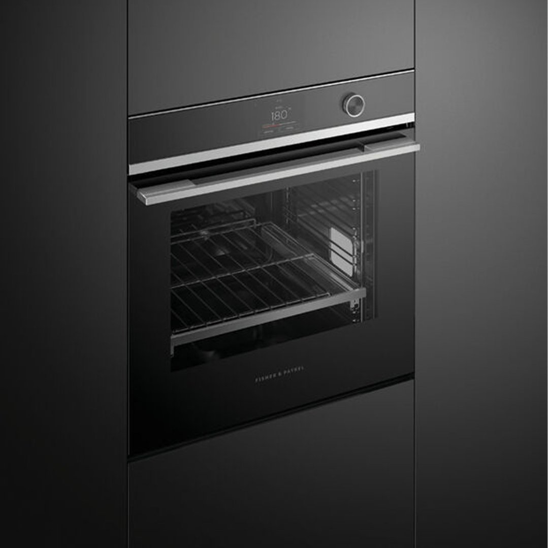 Black built-in oven with digital display and control knob in a dark kitchen
