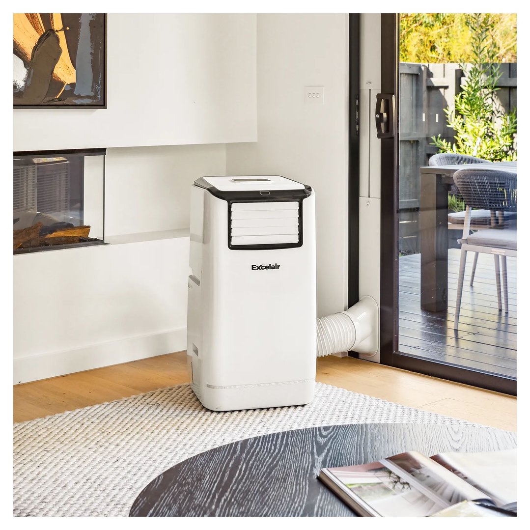 White portable air conditioner in a living room with a fireplace and glass door