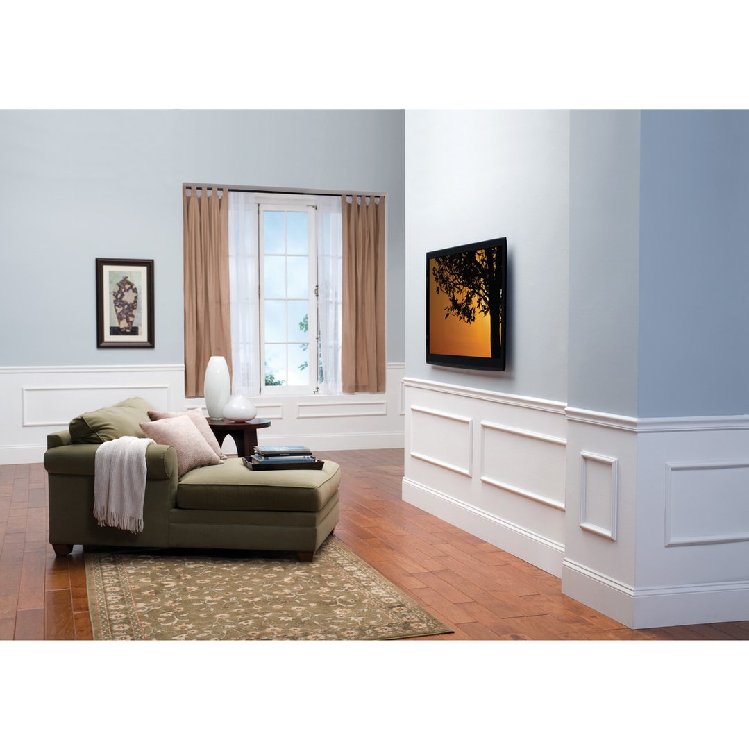A wall-mounted TV in a living room with a chaise lounge and rug