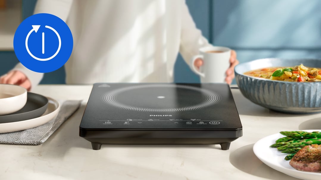 Philips induction cooker on a kitchen counter with food and a person