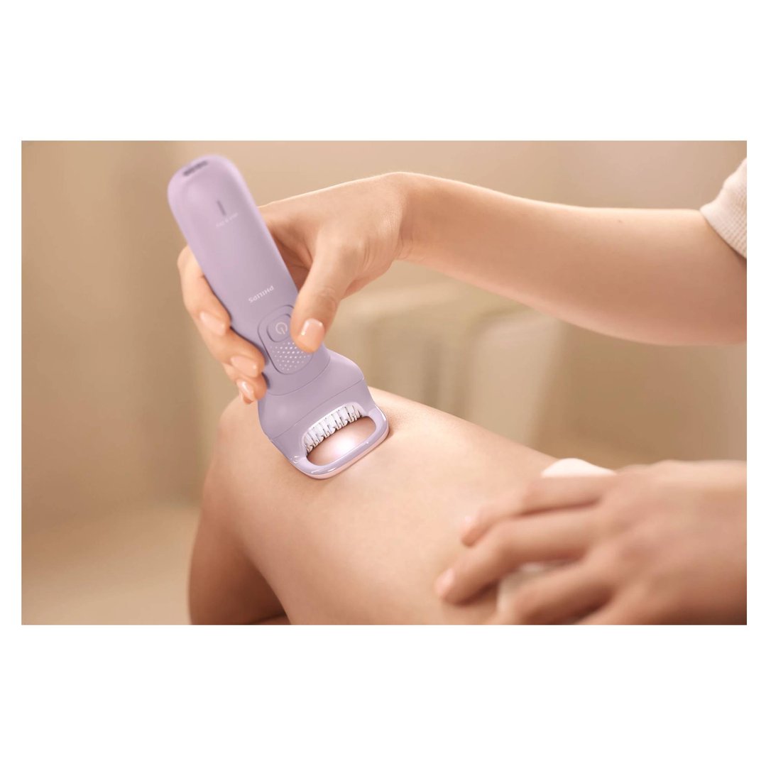 A person using a Philips epilator on their leg, showing the device in action